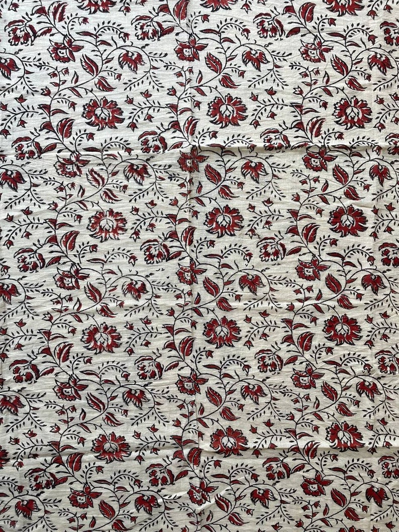 May include: White fabric with a repeating pattern of red and black floral designs.