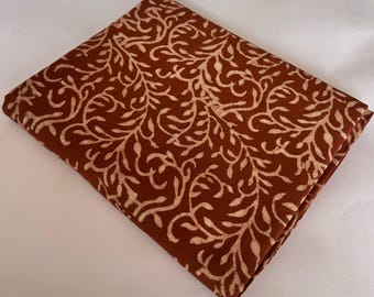 May include: A brown fabric with a white floral pattern. The fabric has a soft, natural texture and is perfect for crafting projects.