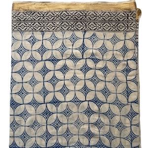 May include: A white cotton fabric with a blue and black geometric pattern. The fabric has a gold trim around the edges.