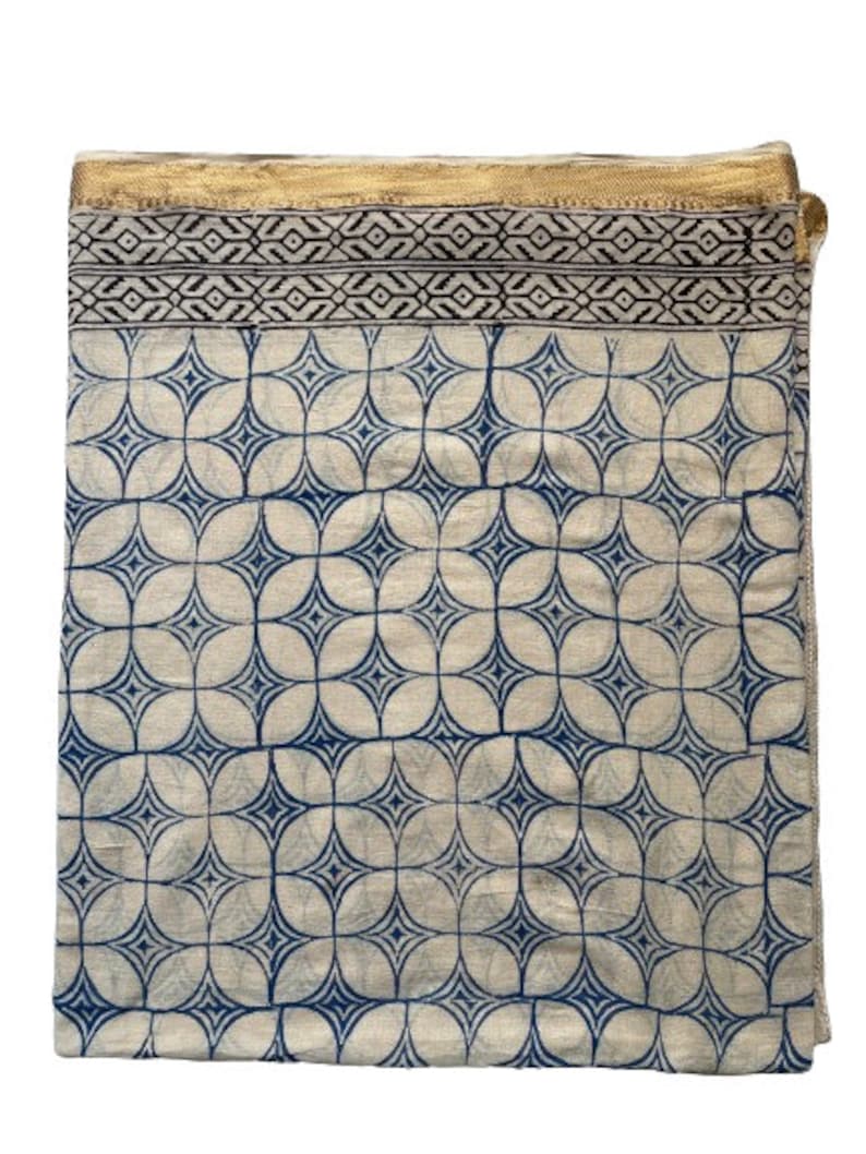 May include: A white cotton fabric with a blue and black geometric pattern. The fabric has a gold trim around the edges.