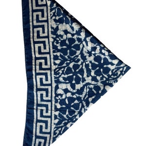May include: A blue bandana with a white floral pattern and a white Greek key border.