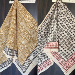 May include: Two cotton fabric squares with different geometric patterns. One square is white with black geometric patterns and a red border. The other square is white with brown geometric patterns and a black border.