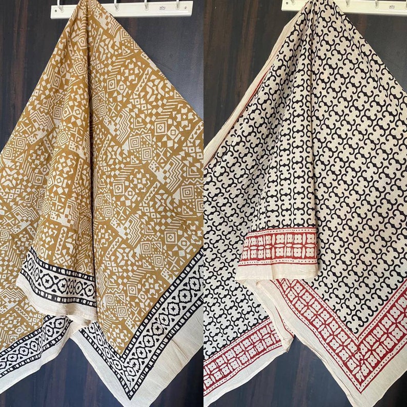 May include: Two cotton fabric squares with different geometric patterns. One square is white with black geometric patterns and a red border. The other square is white with brown geometric patterns and a black border.