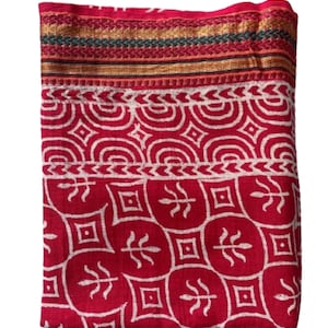 May include: A red cotton fabric with a white geometric pattern. The fabric has a gold and green border.