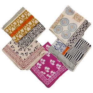 May include: A collection of six square patterned cloth napkins. The napkins feature various designs, including floral, geometric, and striped patterns in colors like yellow, orange, black, white, blue, and pink. The napkins are arranged in a fan shape.