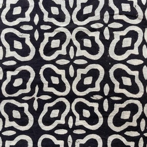 May include: Black and white fabric with a repeating pattern of stylized flowers. The flowers are outlined in white and have a black center.
