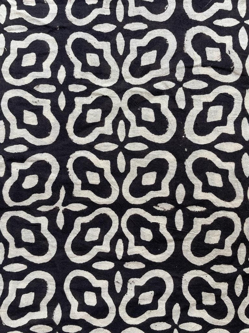 May include: Black and white fabric with a repeating pattern of stylized flowers. The flowers are outlined in white and have a black center.