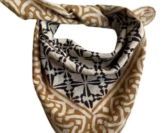 May include: A brown and white patterned bandana with a black geometric design. The bandana is folded into a triangle shape.