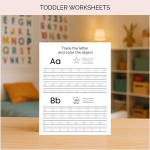 Op de afbeelding: Een wit werkblad voor peuters met de tekst "Trek de letter over en kleur het object in". Het werkblad bevat de letters Aa en Bb, met overtreklijnen en illustraties van een ster en een beer. Op de achtergrond een kleurrijke alfabetkaart.