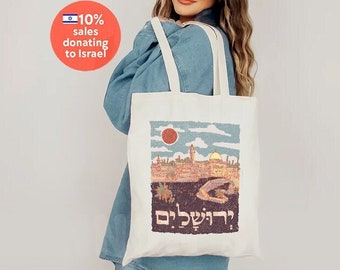 Könnte beinhalten: Eine weiße Canvas-Tragetasche mit einer bunten Illustration einer Stadtlandschaft und dem hebräischen Text "ירושלים" (Jerusalem).
