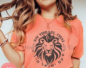 May include: Orange t-shirt with the text "AM YISRAEL CHAI" encircling a lion's head graphic. The shirt has a crew neck and short sleeves. The text "Jew got it Art" is printed at the bottom.