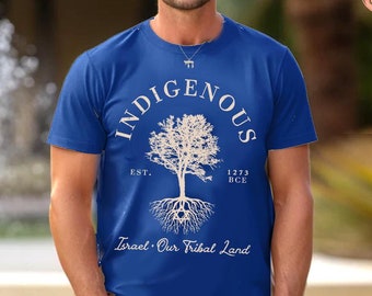Op de afbeelding: Een koningsblauw T-shirt met korte mouwen en een witte afbeelding van een boom met zichtbare wortels. De tekst luidt INDIGENOUS, EST. 1273 BCE en Israel Our Tribal Land. Een Davidster is verwerkt in het wortelsysteem van het ontwerp.