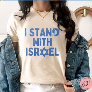 May include: A white t-shirt with the text "I Stand With Israel" in blue letters and a blue Star of David.