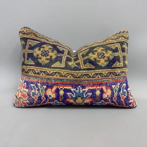 May include: A decorative pillow with a blue, green, and red patterned fabric. The pillow has a traditional design with intricate details.