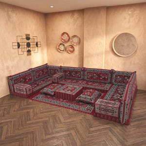 May include: A modular floor sofa set featuring a red, black, and white geometric pattern. The set includes multiple rectangular floor cushions, backrests, armrests, and a central square ottoman, all upholstered in a matching woven textile fabric.