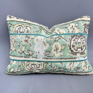 Puede incluir: Una almohada rectangular de tejido suave y tejido, con un patrón verde y blanco y un borde turquesa.