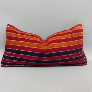 May include: A striped pillow with red, orange, and black stripes. The pillow is made of a soft, woven fabric.