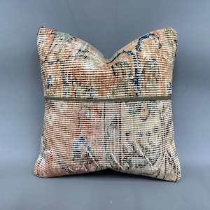 May include: A decorative throw pillow with a colorful, abstract pattern in shades of blue, green, and orange. The pillow has a brown trim around the edges.