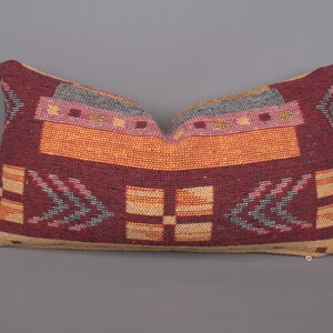 May include: A rectangular pillow with a geometric pattern in shades of red, orange, yellow, and gray. The pillow has a zipper closure on the bottom.