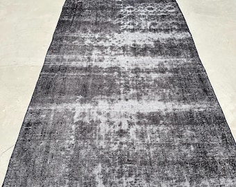 May include: A black and white distressed rug with a faded, abstract pattern. The rug has a subtle sheen and a textured surface.