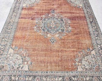 May include: A vintage rug with a faded red background and a central medallion in shades of blue, beige, and black. The rug has a border with intricate floral patterns in shades of blue, beige, and black.