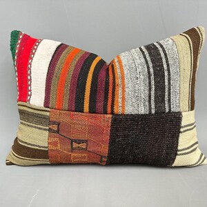 May include: A rectangular patchwork pillow with a variety of colorful stripes and patterns in shades of brown, red, orange, white, and black.