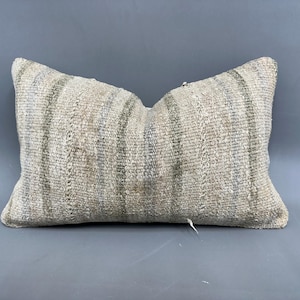 May include: A white and gray striped throw pillow with a woven texture. The pillow is made of a soft, natural material and has a slightly distressed look.