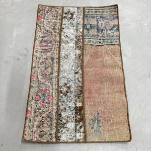 May include: A rectangular patchwork rug with a brown, white, and pink design. The rug is made of different pieces of fabric sewn together.