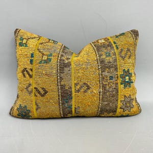 May include: A rectangular decorative pillow with a yellow and brown striped pattern. The pillow features a textured weave with small geometric shapes in teal and brown. The pillow has a yellow border.
