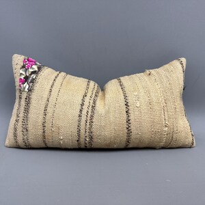 May include: A white and black striped throw pillow with pink and silver embellishments.