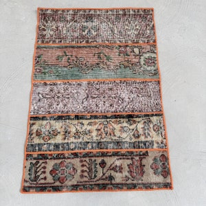 May include: A multi-colored vintage rug with an orange border. The rug is made of different patterned fabrics sewn together. The rug has a floral design.