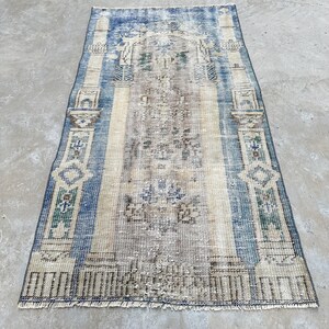 May include: A vintage blue and cream rug with a geometric pattern. The rug has a fringed edge and is made of wool.