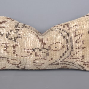 May include: A beige and brown patterned throw pillow with a woven texture.