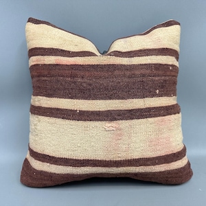 May include: A striped throw pillow with a brown and white pattern. The pillow is made of a soft, woven fabric.