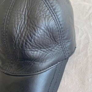 May include: A black leather baseball cap with a curved brim and a button on top.