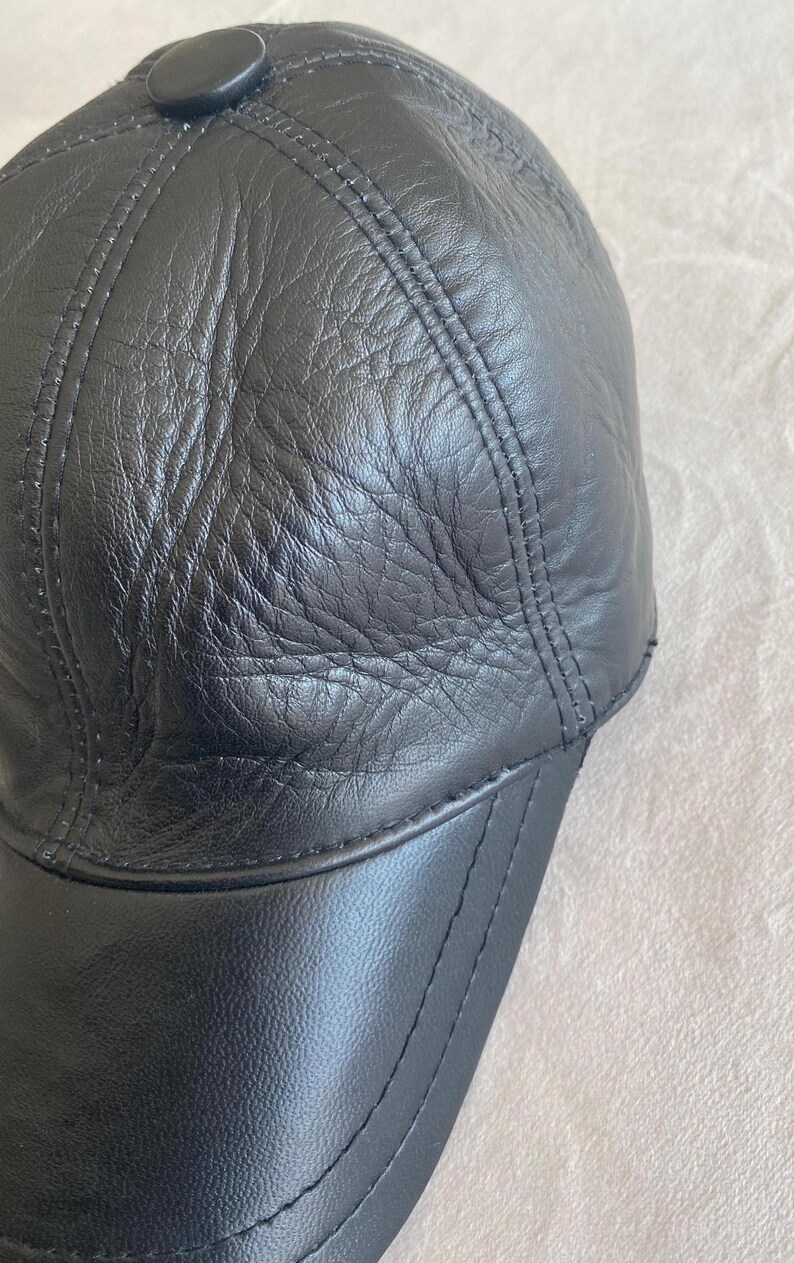 May include: A black leather baseball cap with a curved brim and a button on top.
