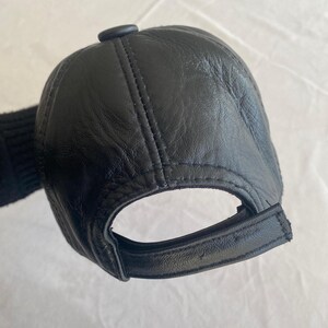 May include: A black leather baseball cap with a stitched brim and a button on the top.