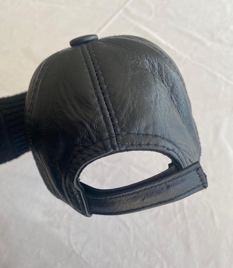 May include: A black leather baseball cap with a stitched brim and a button on the top.