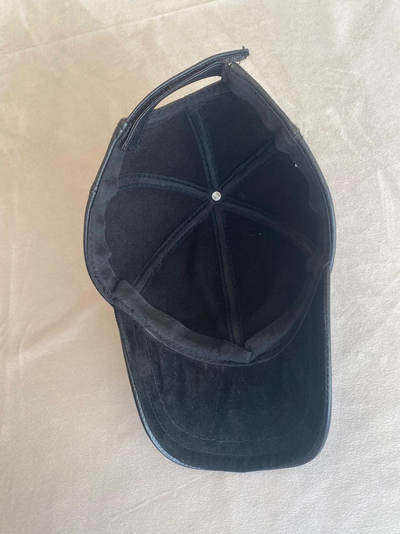 May include: Black leather baseball cap with a curved brim. The cap has a black fabric lining.