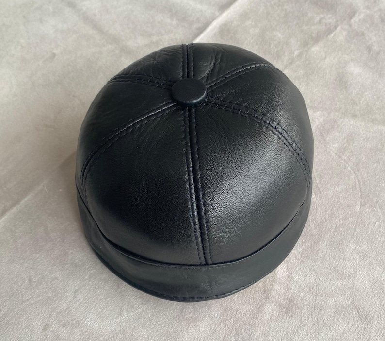 May include: A black leather baseball cap with a stitched design.