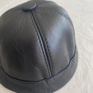 May include: A black leather baseball cap with a button on top.