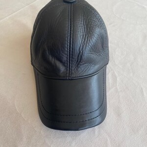 May include: A black leather baseball cap with a stitched brim and a button on top.