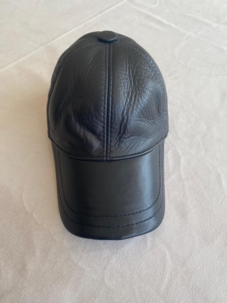 May include: A black leather baseball cap with a stitched brim and a button on top.