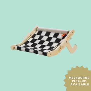 Puede incluir: Una cama de madera para mascotas con una almohadilla de vellón a cuadros en blanco y negro. La cama es plegable y tiene un diseño sencillo.