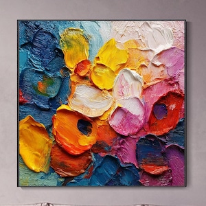 Op de afbeelding: Een vierkant canvas schilderij met dikke, getextureerde impasto penseelstreken in een levendig palet van diepblauw, heldergeel, oranje, magenta en wit. De abstracte compositie toont gelaagde verfaanbrengingen die een reliëfeffect creëren.