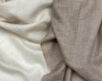 May include: Two rectangular scarves with a visible woven texture and frayed edges. One scarf is a solid off-white color, while the other is a solid light taupe or beige color. Both pieces of fabric are draped in soft, overlapping folds.