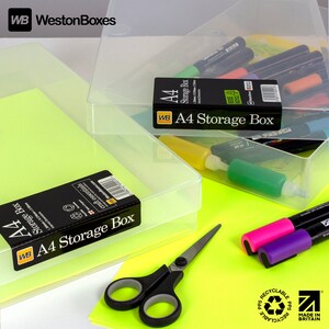 May include: Two clear plastic storage boxes with the label "A4 Storage Box" on the front. The boxes are made of recyclable polypropylene and are made in Britain. The boxes are sitting on a bright yellow surface with a pair of scissors and markers.