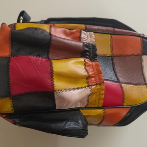 Peut inclure: Un sac patchwork multicolore avec une fermeture &eacute;clair et une poign&eacute;e noires. Le sac pr&eacute;sente une vari&eacute;t&eacute; de couleurs, dont le rouge, le jaune, l'orange, le marron et le noir. Le sac est en cuir et pr&eacute;sente un design g&eacute;om&eacute;trique unique.