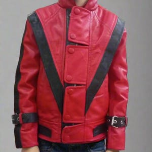 May include: A red leather jacket with black stripes and accents, featuring a high collar and button details. The jacket has a V-shaped design on the front and is worn with blue jeans. The jacket has a buckle on the sleeves.