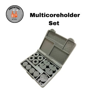 Op de afbeelding: Een grijze plastic koffer met een verscheidenheid aan zwarte en grijze spoelhouders. De koffer is open en de houders zijn zichtbaar. De koffer heeft de tekst "Multicoreholder Set" erop gedrukt.
